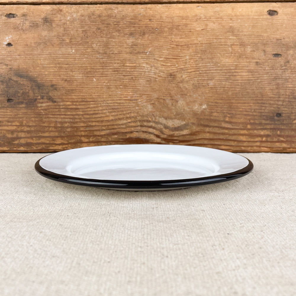 Assiette plate en émail blanc liseré noir