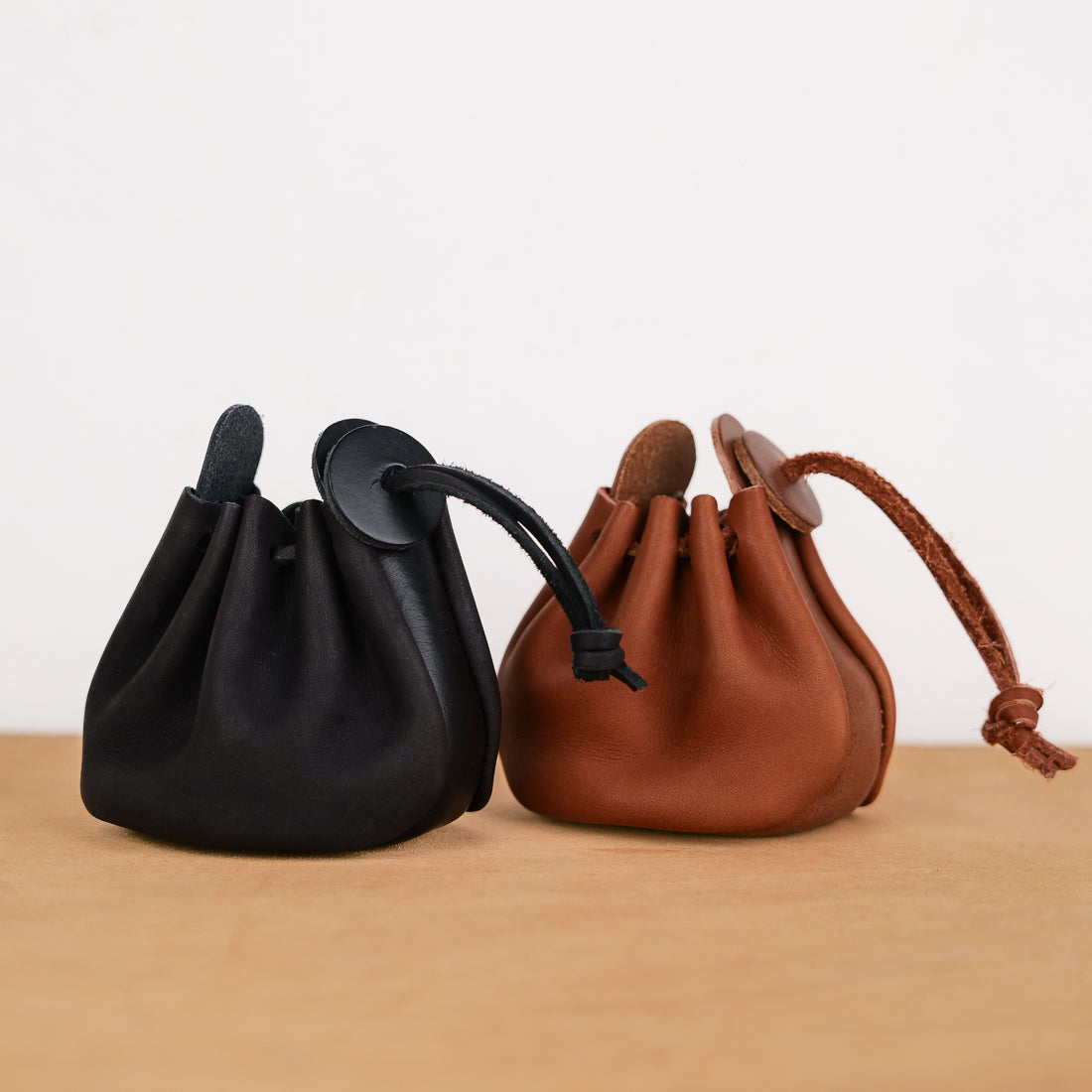 Black and tan soft leather drawstring coin purses, both colorways side by side, 8 x 10 cm