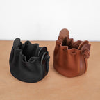 Deux bourses cuir souple noir et cognac côte à côte, coloris comparés, fermeture cordon, 8 x 10 cm